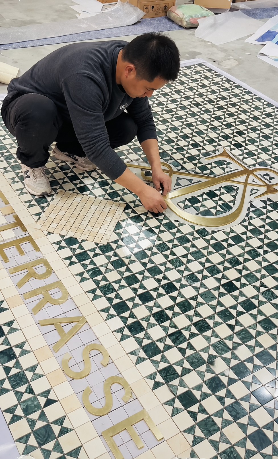 Craftsman assembling geometric green and white mosaic artwork by hand